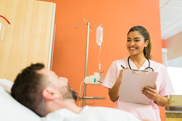 smiling-female-doctor-talking-male-patient-while-reading-reports-hospital