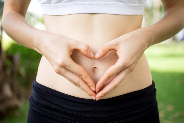 close-up-female-hands-shaping-heart-belly