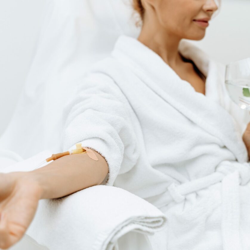 close up calm female patient sitting with tube needle during iv infusion girl holding glass with lemon water relaxing 1